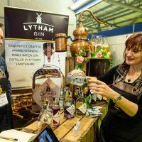 Lytham Gin display stall with a man behind the counter and a lady pouring a drink