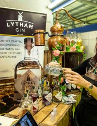 Lytham Gin display stall with a man behind the counter and a lady pouring a drink