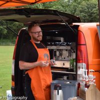 Man standing by a coffee van serving people
